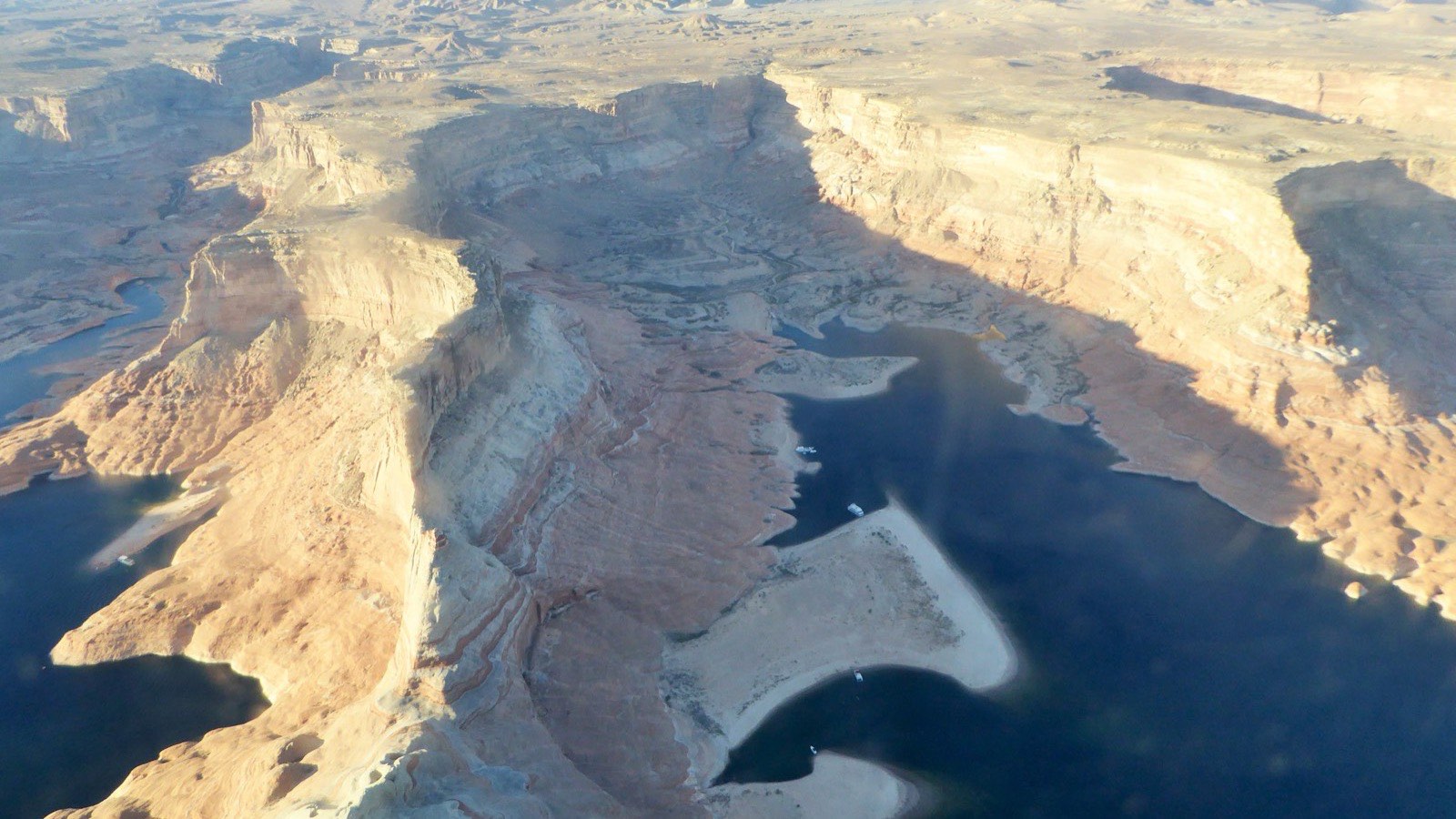Aerial photo of Lake Powell's red-rock buttes and bays, with the pale bathtub ring and exposed sandbars marking how far the water has dropped